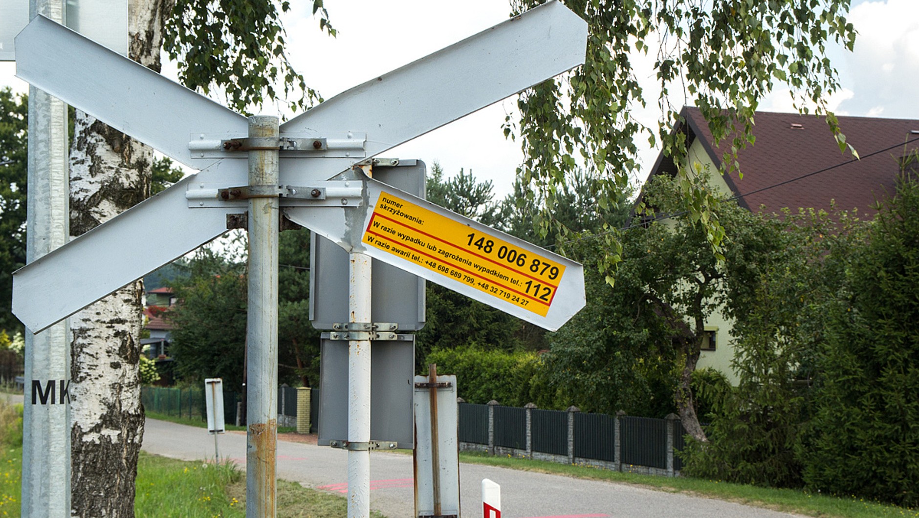 Na przejściach przez tory i na przejazdach niższych kategorii naklejka znajduje się na ramieniu znaku stojącego przy torach