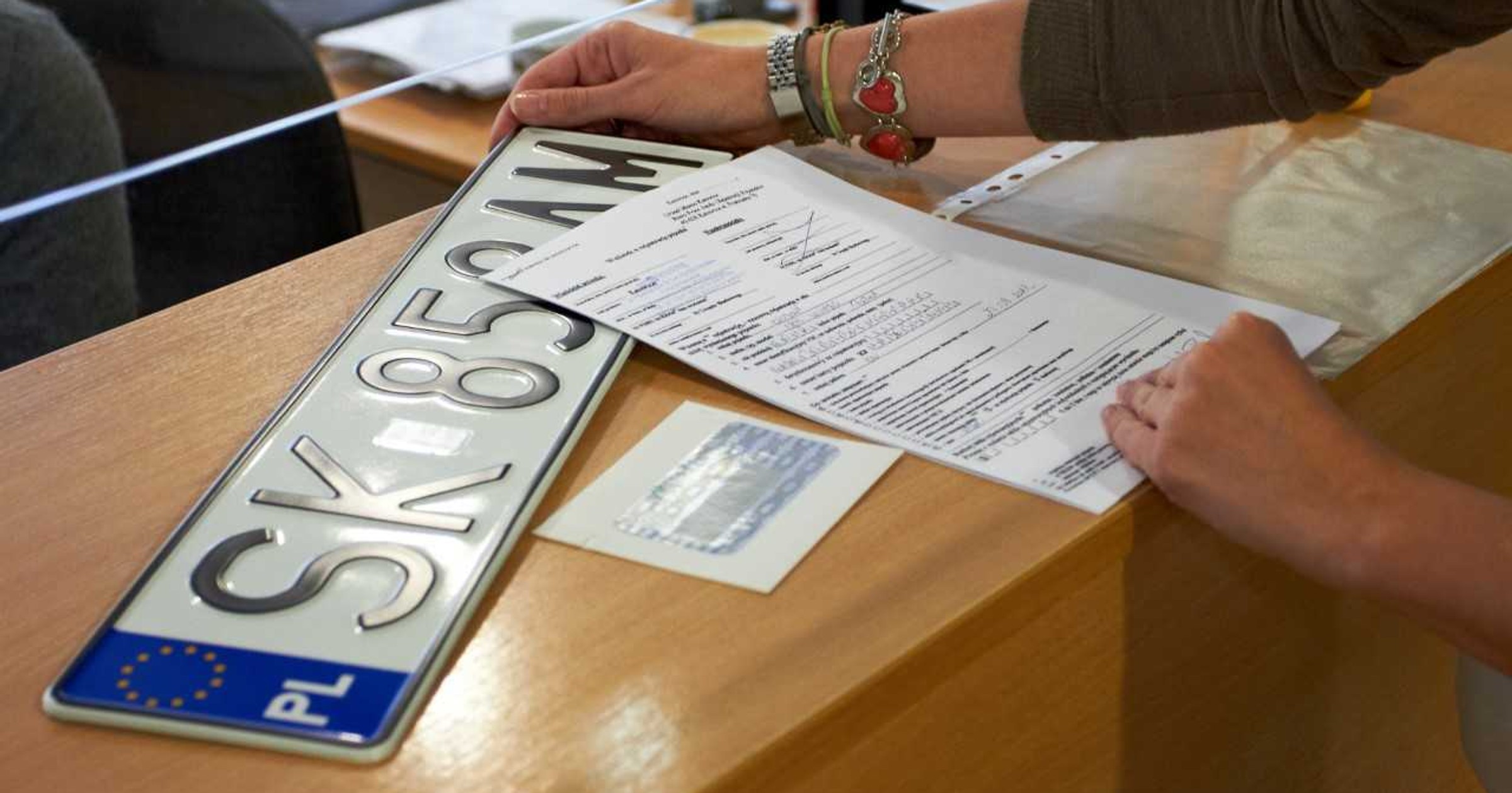 Kierowca z tablicą rejestracyjną w urzędzie