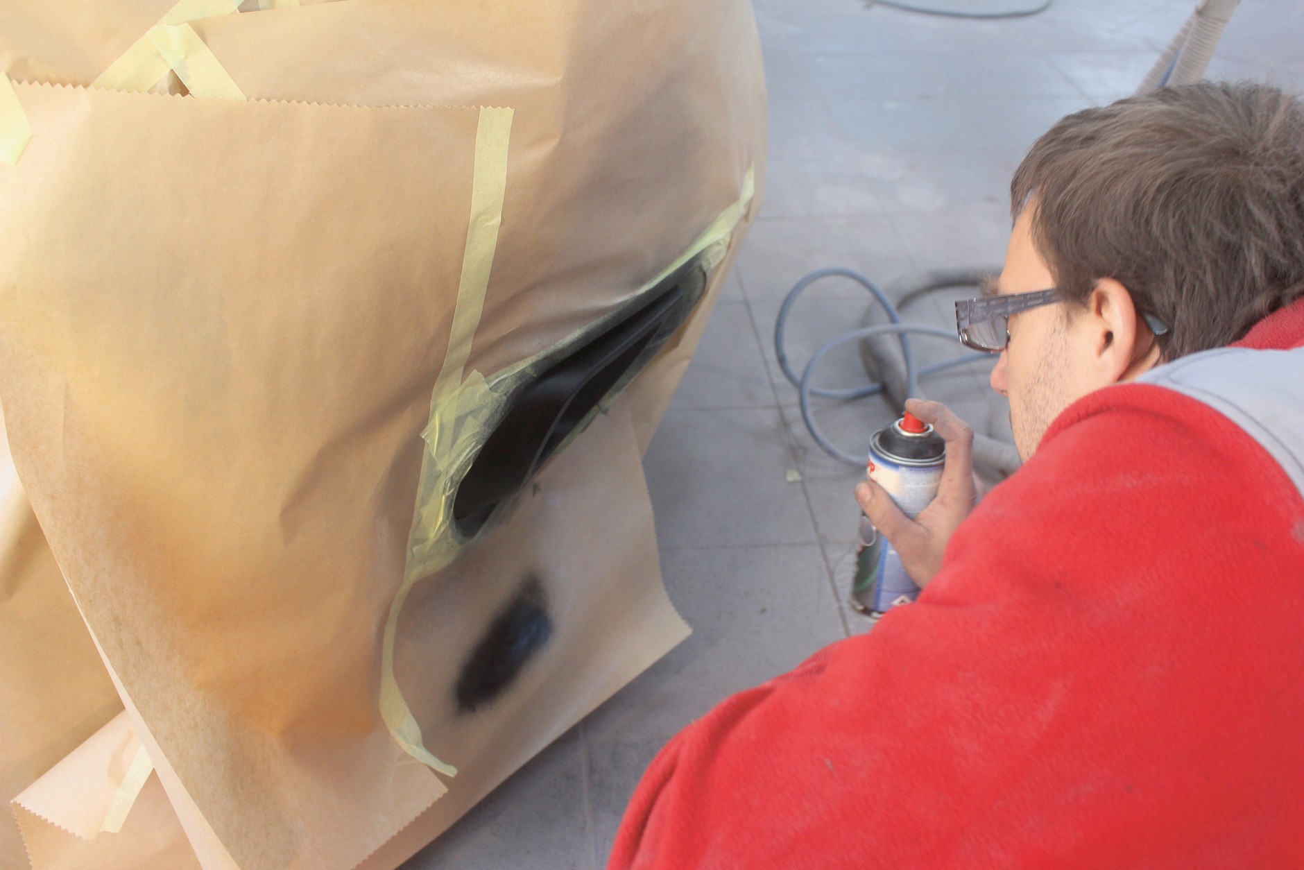 Renowacja czarnych listew i zderzaków w aucie: używając lakieru strukturalnego, należy zabezpieczyć sąsiadujące elementy papierem. Uwaga – papier jest dużo lepszy niż folia, od folii lakier odbija się, robiąc dookoła bałagan!