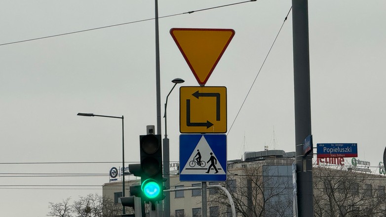 Znak drogowy informujący o bezkolizyjnym torze jazdy przy lewoskręcie