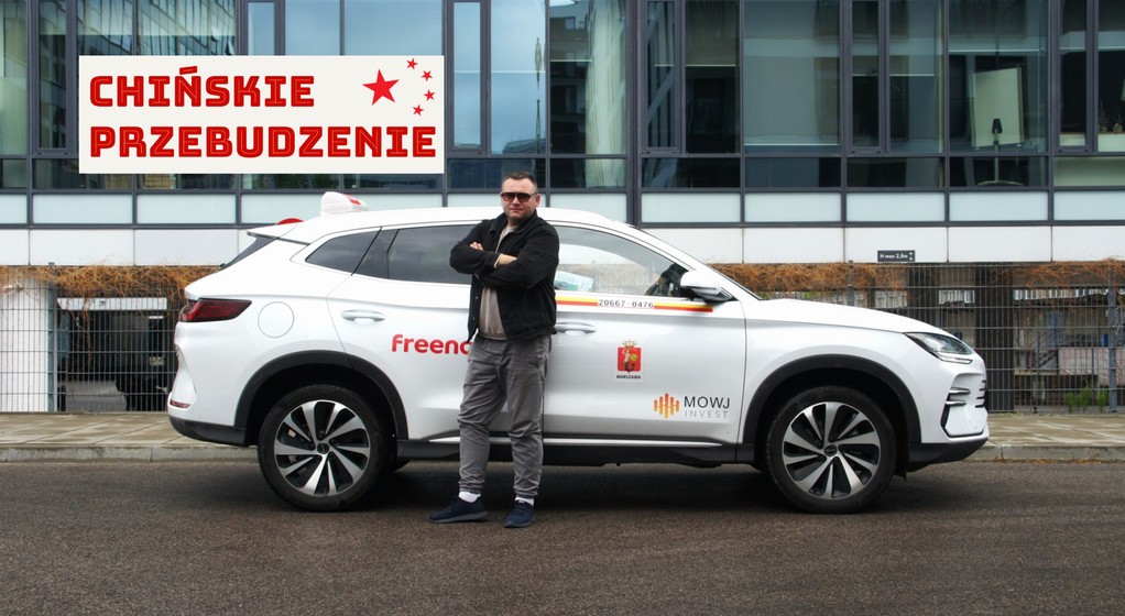 Taksówkarz Marcin Zawodzian na tle swojego chińskiego SUV-a marki BYD