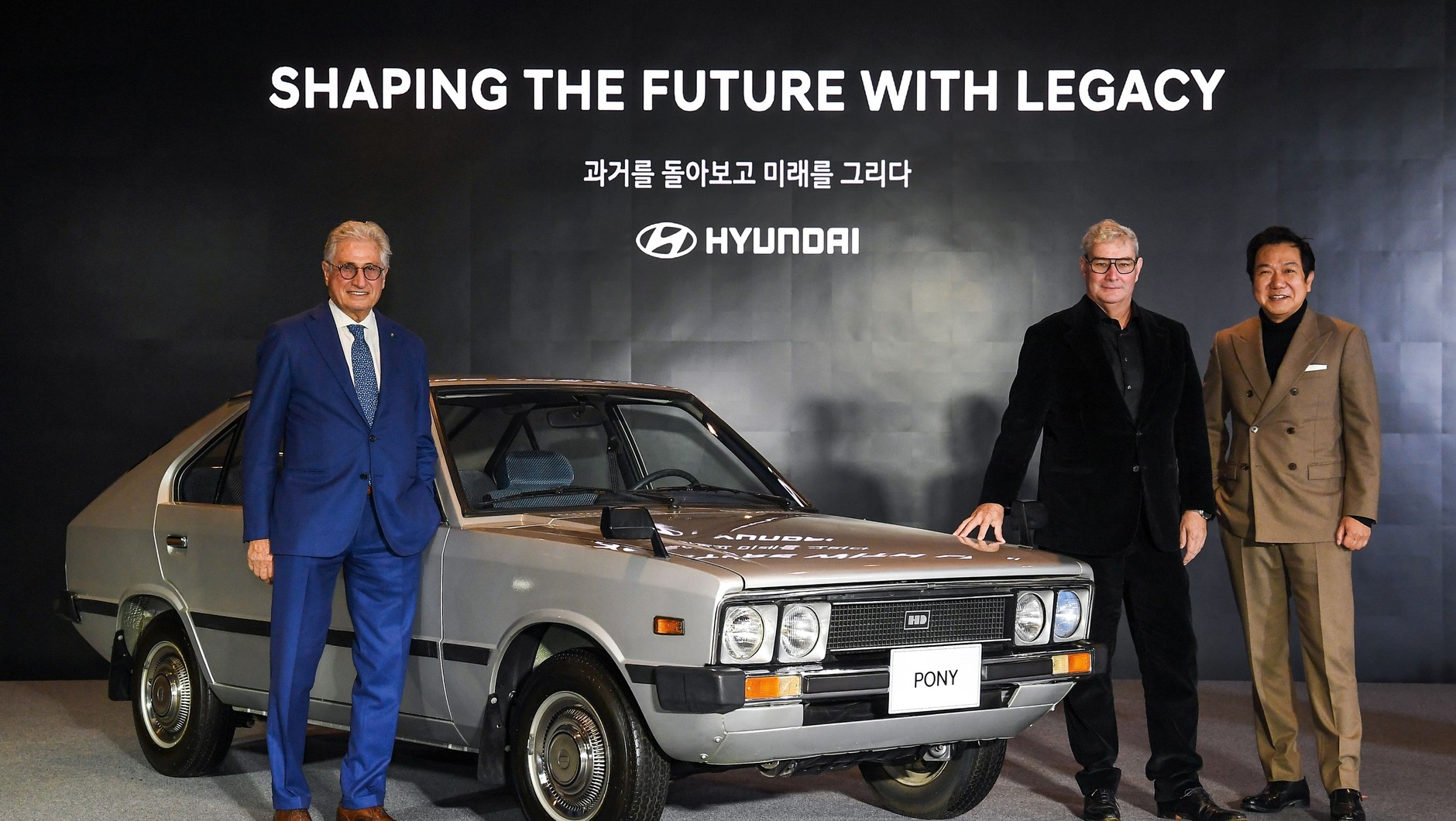 Od lewej Giorgio Giugiaro oraz Luc Donckerwolke i SangYup Lee, dwaj najważniejsi styliści Hyundaia. Między nimi Hyundai Pony I (1975-1981).