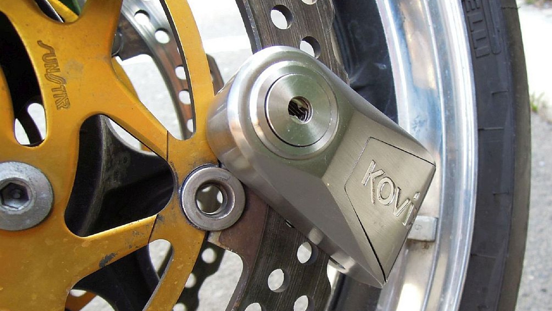 Blokada motocyklowa z alarmem Kovix KNL14 zapięta na tarczy hamulcowej