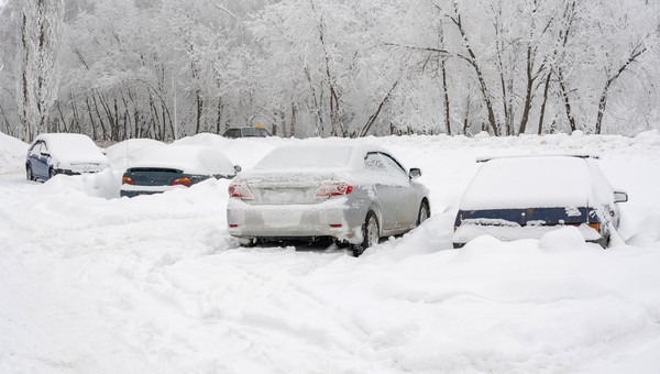 Zasypane śniegiem samochody na nieodśnieżonym parkingu