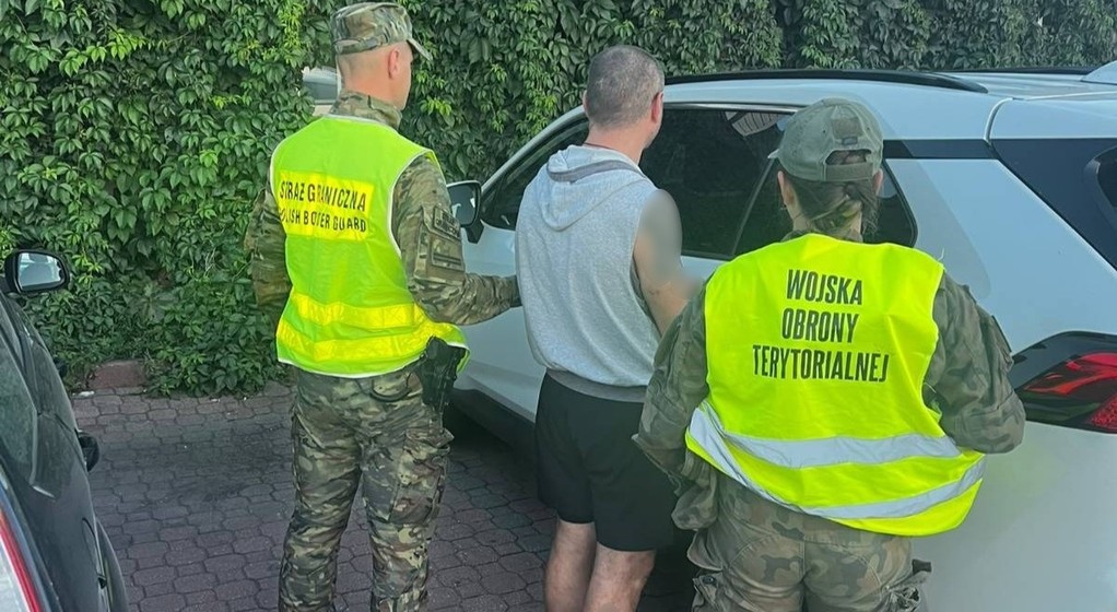 Funkcjonariusze Straży Granicznej i Wojsk Obrony Terytorialnej z zatrzymanym kierowcą na tle skradzionej Toyoty RAV4