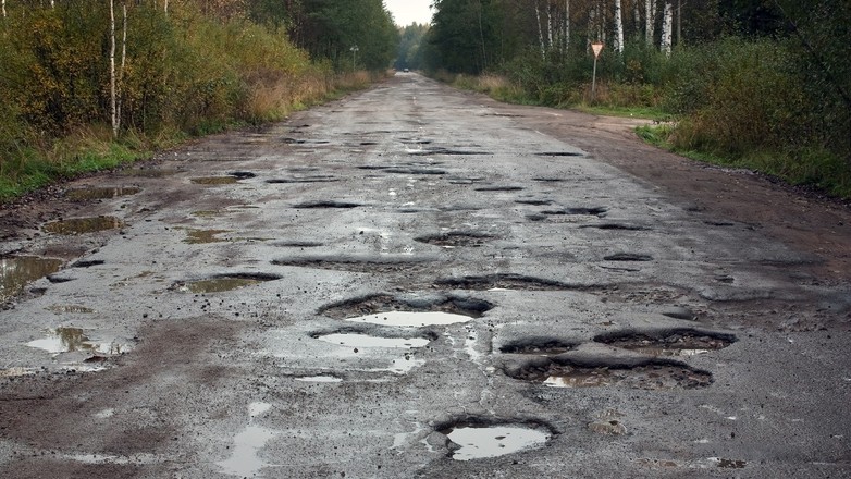 Dziurawa droga z rozległymi uszkodzeniami nawierzchni