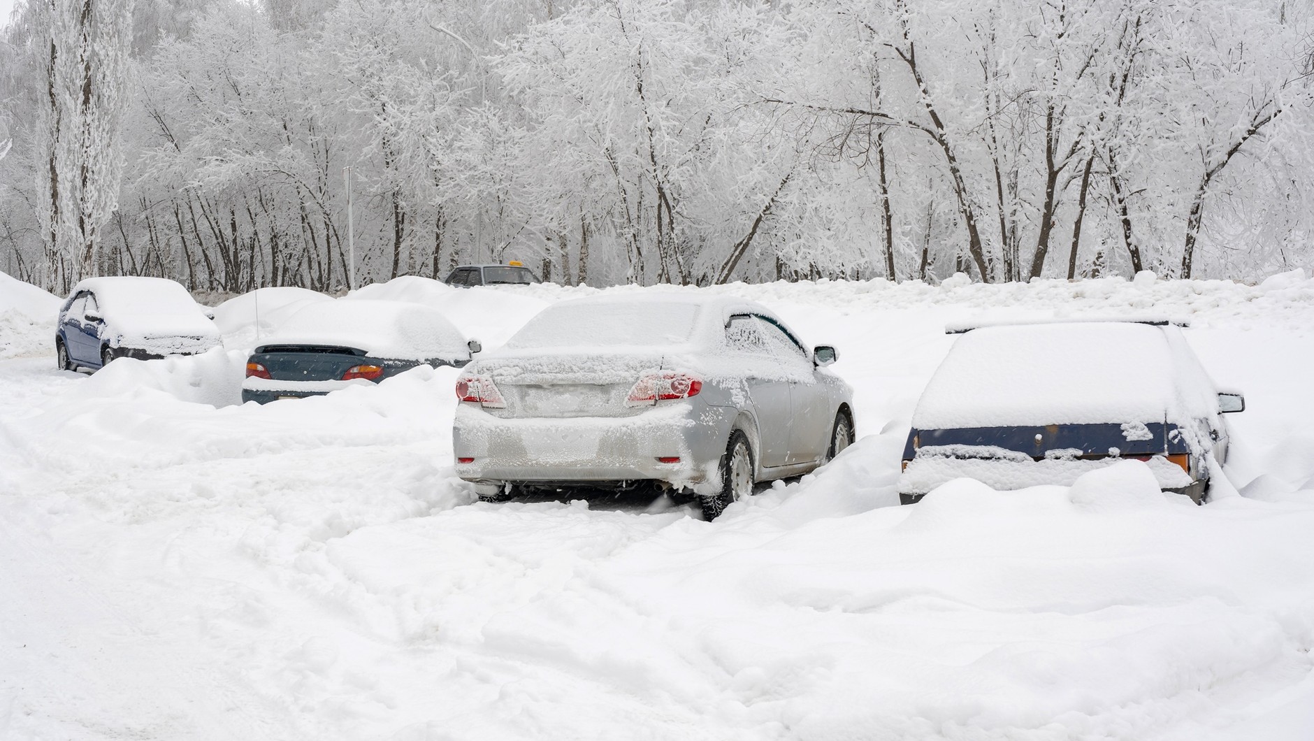 Zasypane śniegiem samochody na nieodśnieżonym parkingu