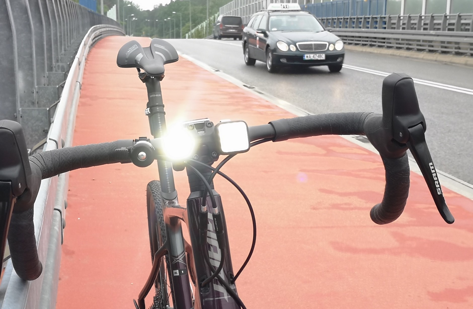 To zdjęcie dość dobrze oddaje różnice w widoczności w dzień lampek z pojedynczym LED-em o wysokiej mocy (ostrzejsze, lepiej widoczne światło – tu lampka Bontrager Ion 200 rt) a lampką z większą liczbą modułów SMD (tu: Knog Blinder MOB). Ta druga też jest widoczna, ale emituje łagodniejsze, bardziej rozproszone światło, mniej widoczne zwłaszcza przy słonecznej pogodzie. Tę słabość neutralizuje tryb szybkiego migania, który zwraca uwagę kierowców