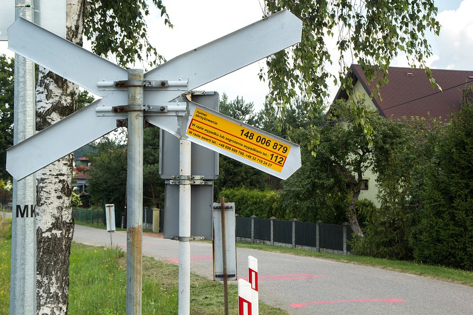 Na przejściach przez tory i na przejazdach niższych kategorii naklejka znajduje się na ramieniu znaku stojącego przy torach
