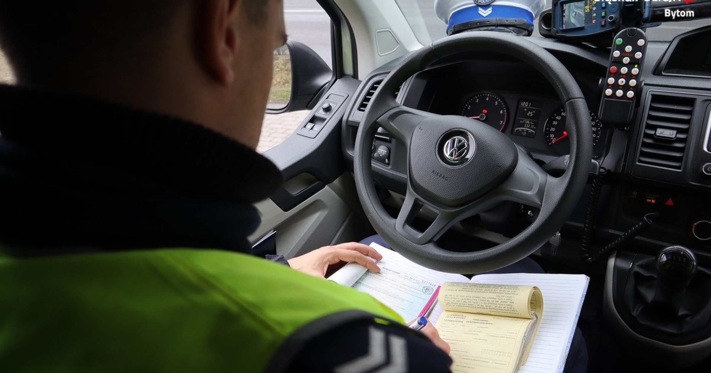 Policjant wypisujący mandat w radiowozie