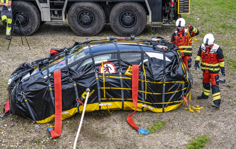 Worek do zabezpieczenia wraku: to kolejna wariacja metody polegającej na zatapianiu nadpalonego wraku auta elektrycznego. Tyle że tu zamiast olbrzymiego metalowego kontenera czy kadzi wykorzystywany jest syntetyczny worek, do którego strażacy pakują wstępnie ugaszone auto. Zestaw jest więc łatwiejszy w transporcie, zajmuje mniej miejsca, a do wypełnienia worka dopasowującego się do rzeczywistych gabarytów auta potrzeba znacznie mniej wody niż przy standardowym topieniu wraku. Tak zapakowane nadpalone auto można bez obaw postawić przy innych wrakach.