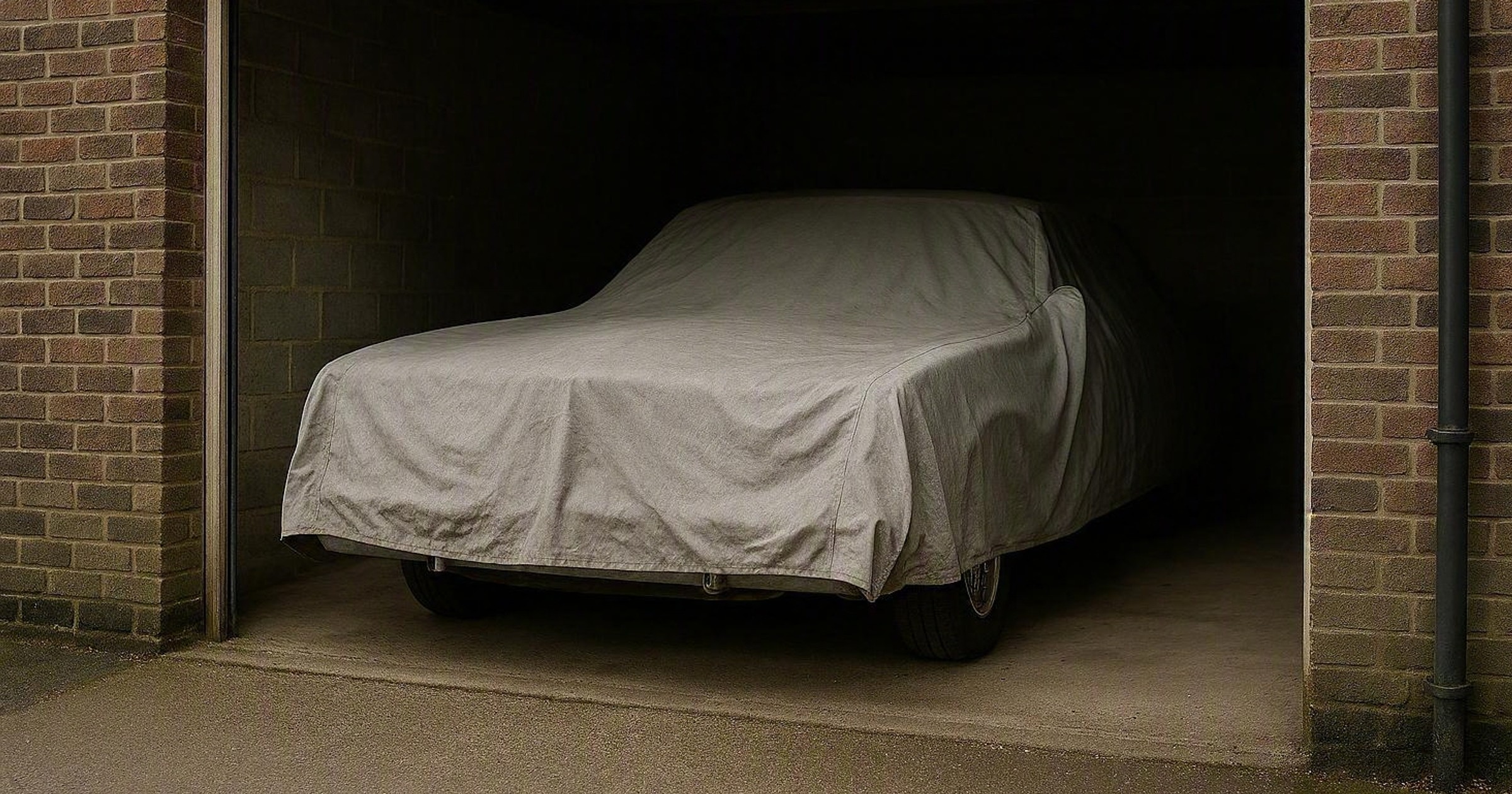 Nakryty pokrowcem zabytkowy samochód stojący w garażu