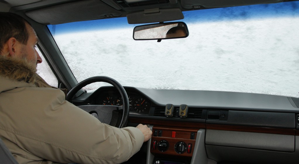 Oblodzona od wewnątrz szyba samochodu: przed rozgrzaniem silnika kierowca nie ma szans na bezpieczną jazdę - po odskrobaniu lodu na szybie natychmiast osadza się szron.