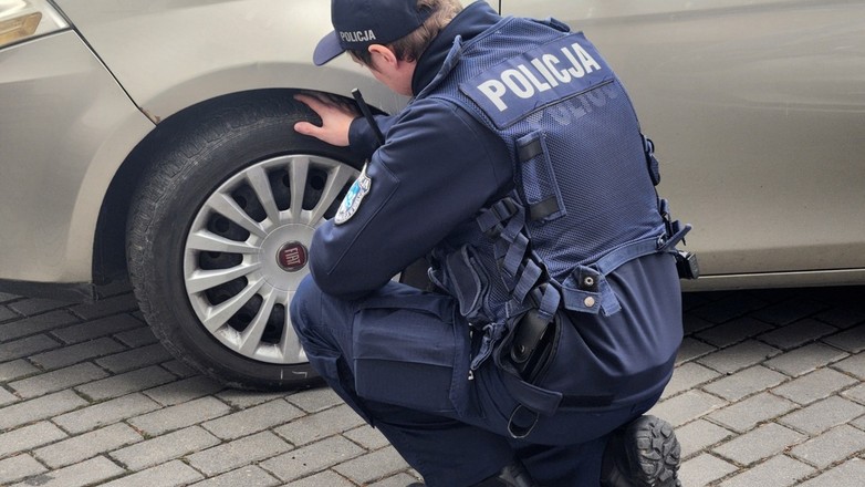 Policjant kontrolujący stan opon w samochodzie