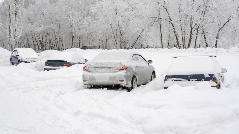 Zasypane śniegiem samochody na nieodśnieżonym parkingu