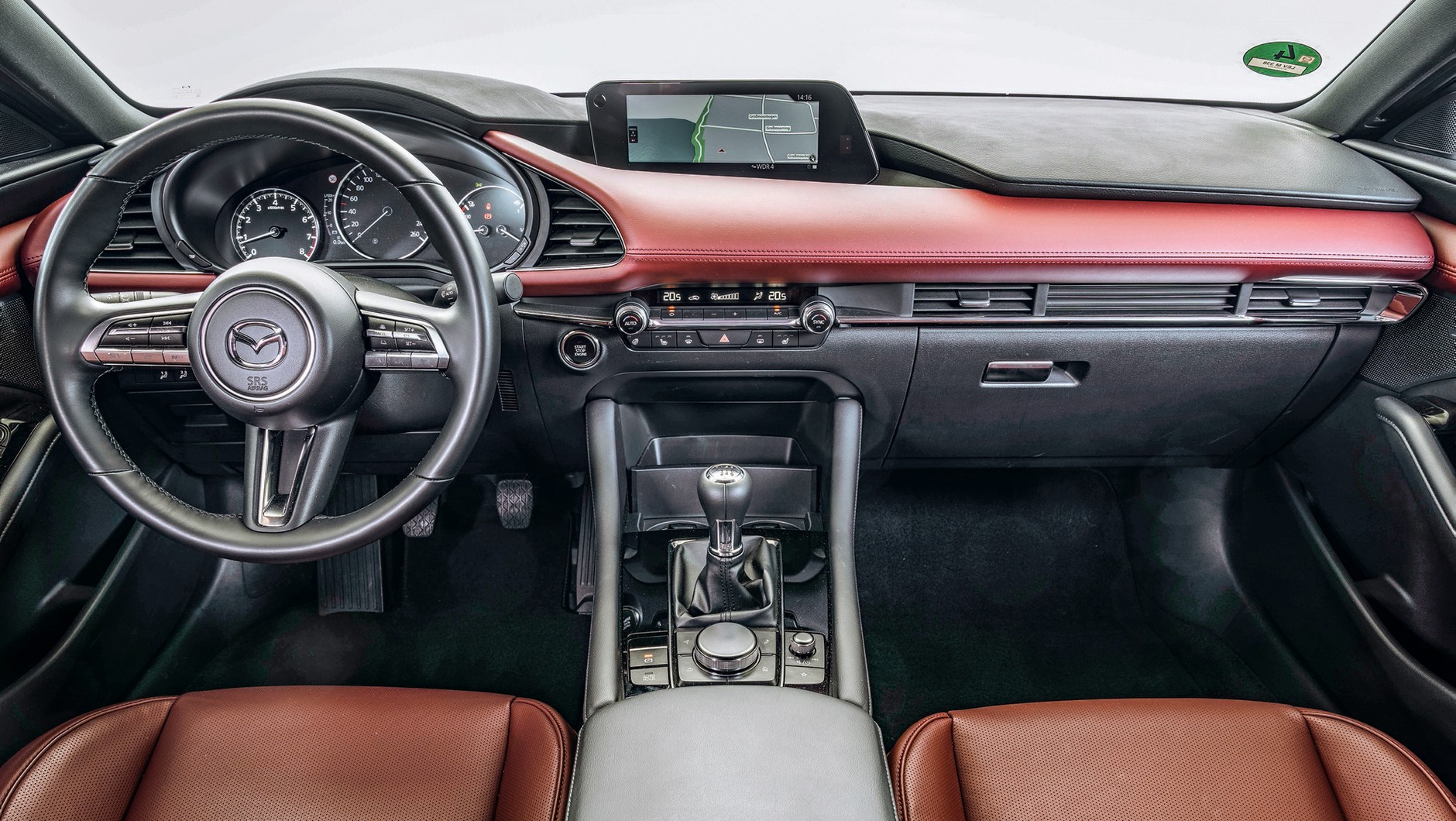 Mazda 3: skórzany element stylistyczny w sumiennie zmontowanym kokpicie, który jakością puka do drzwi klasy premium. W centrum ręczna skrzynia i pokrętło do sterowania centralnym ekranem.