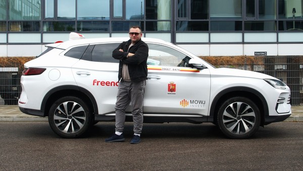 Taksówkarz Marcin Zawodzian na tle swojego chińskiego SUV-a marki BYD