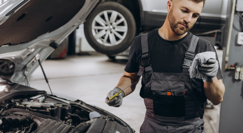 Mechanik kontrolujący stan oleju silnikowego w samochodzie