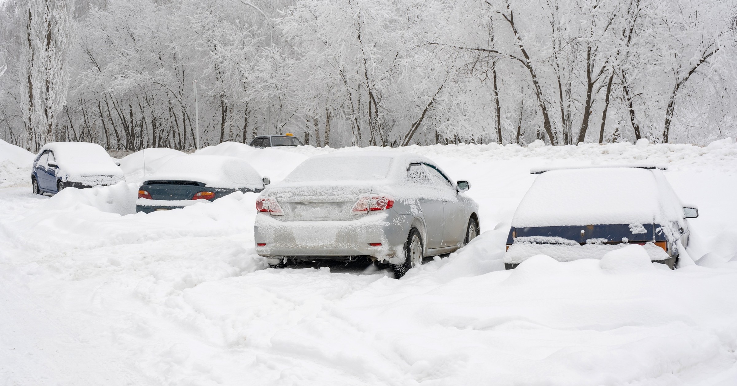 Zasypane śniegiem samochody na nieodśnieżonym parkingu