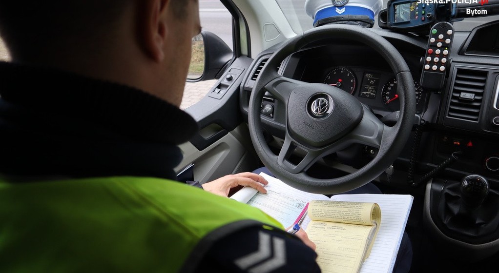 Policjant wypisujący mandat w radiowozie