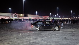 Nielegalny zlot samochodowy. Drift na parkingu pod supermarketem