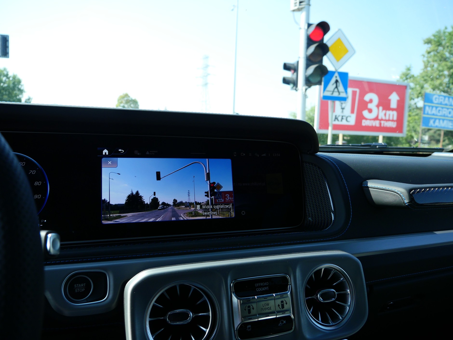 Mercedes G580 EQ: przez małą, niemal pionową przednią szybę wysocy kierowcy ledwo widzą światła. Dlatego, kiedy staniemy na światłach, na ekranie wyświetlany jest widok sygnalizatora.