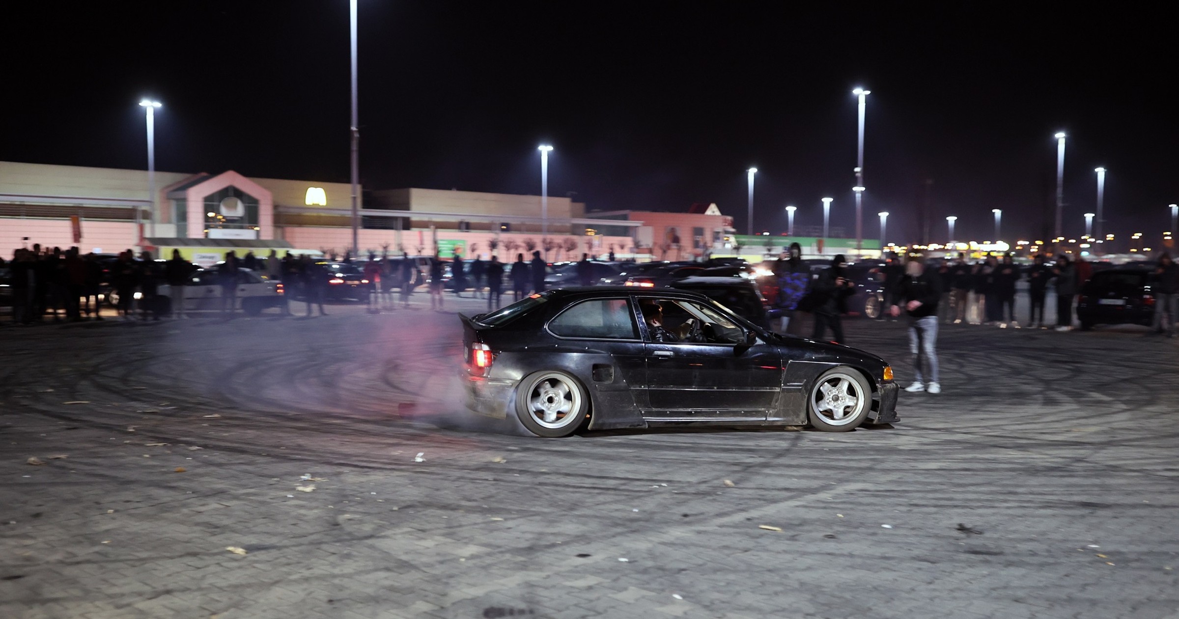 Nielegalny zlot samochodowy. Drift na parkingu pod supermarketem