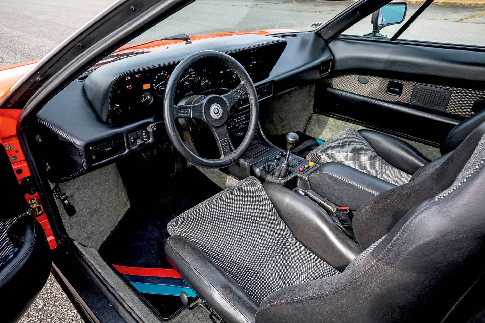 Deskę rozdzielczą obito skórą, ale poza tym we wnętrzu BMW M1 jest raczej skromnie.  Wąskie kubełkowe siedzenia, sterowanie nawiewami z pierwszej serii 3 (E21).