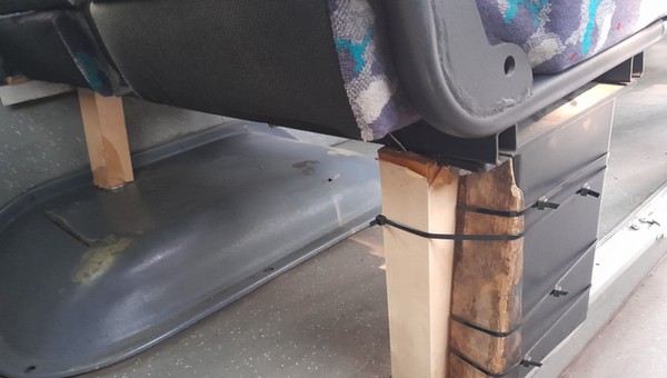 Autobus z fotelami na drewnianych klockach i z pękniętą felgą