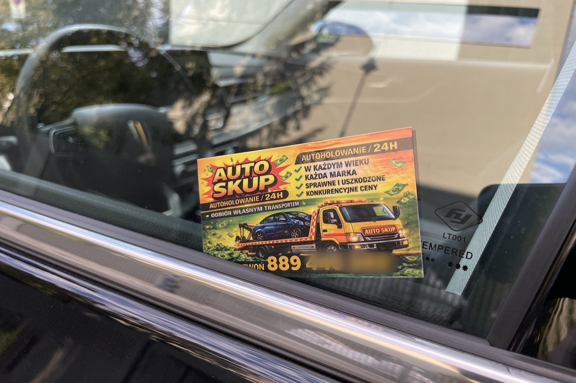 Karteczka auto skupu wetknięta pomiędzy uszczelkę i szybę