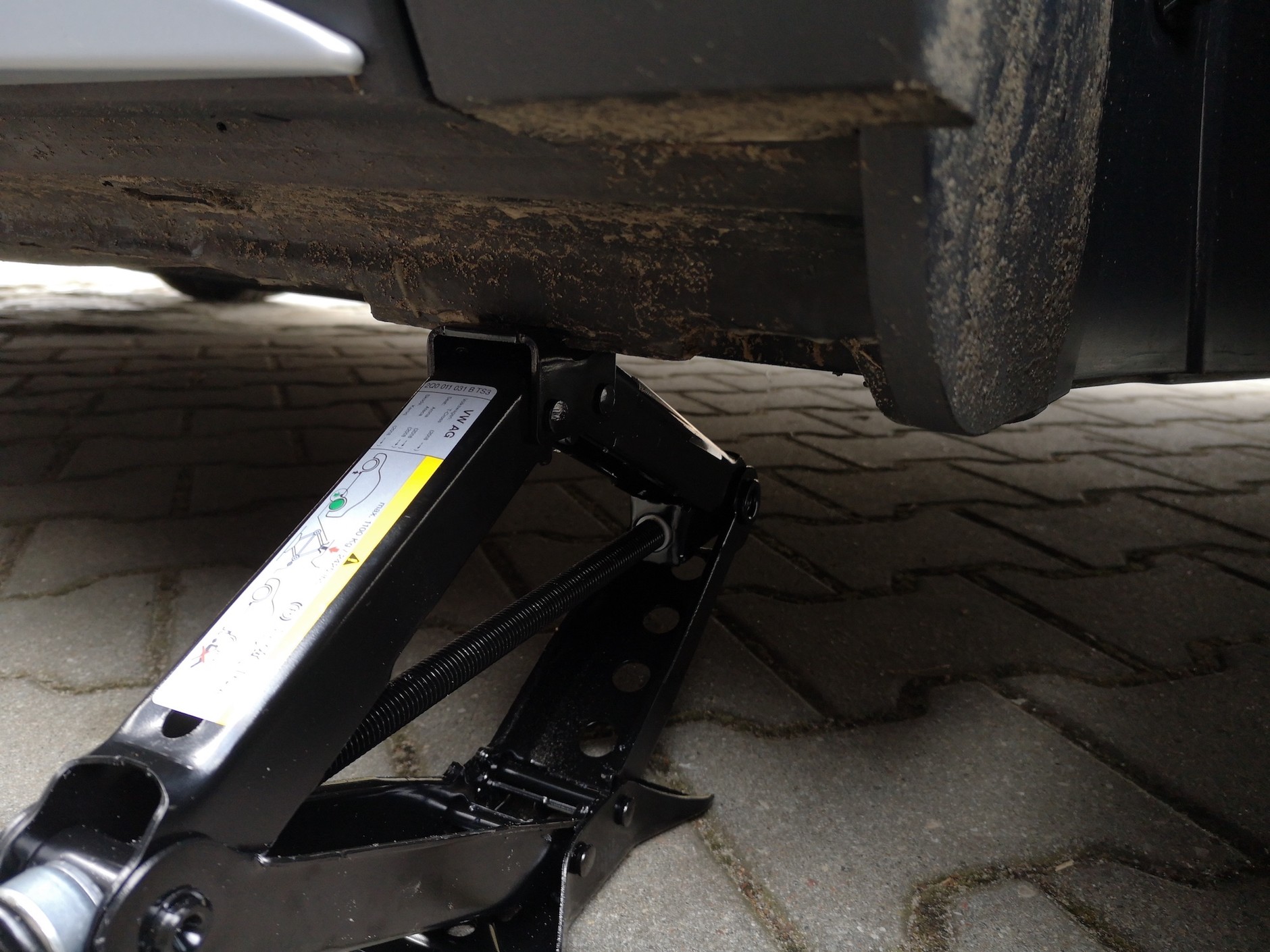 Wymiana koła krok po kroku: podnośnik musi stać na stabilnej powierzchni. Przed uniesieniem samochodu zaciągnij hamulec, podłóż coś pod koła, żeby auto się nie stoczyło.