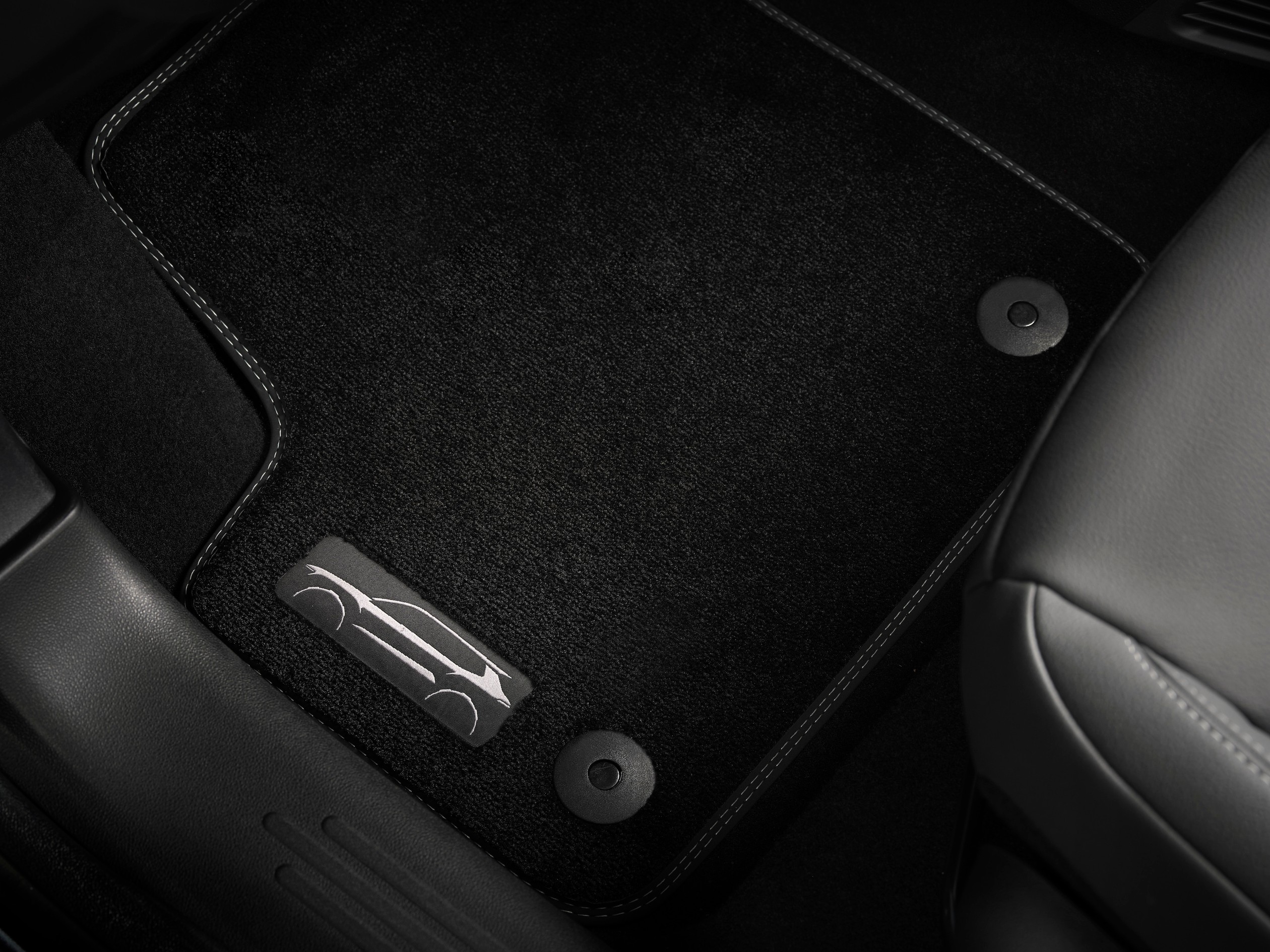 Dywaniki podłogowe klasy premium mają logo z sylwetką samochodu.