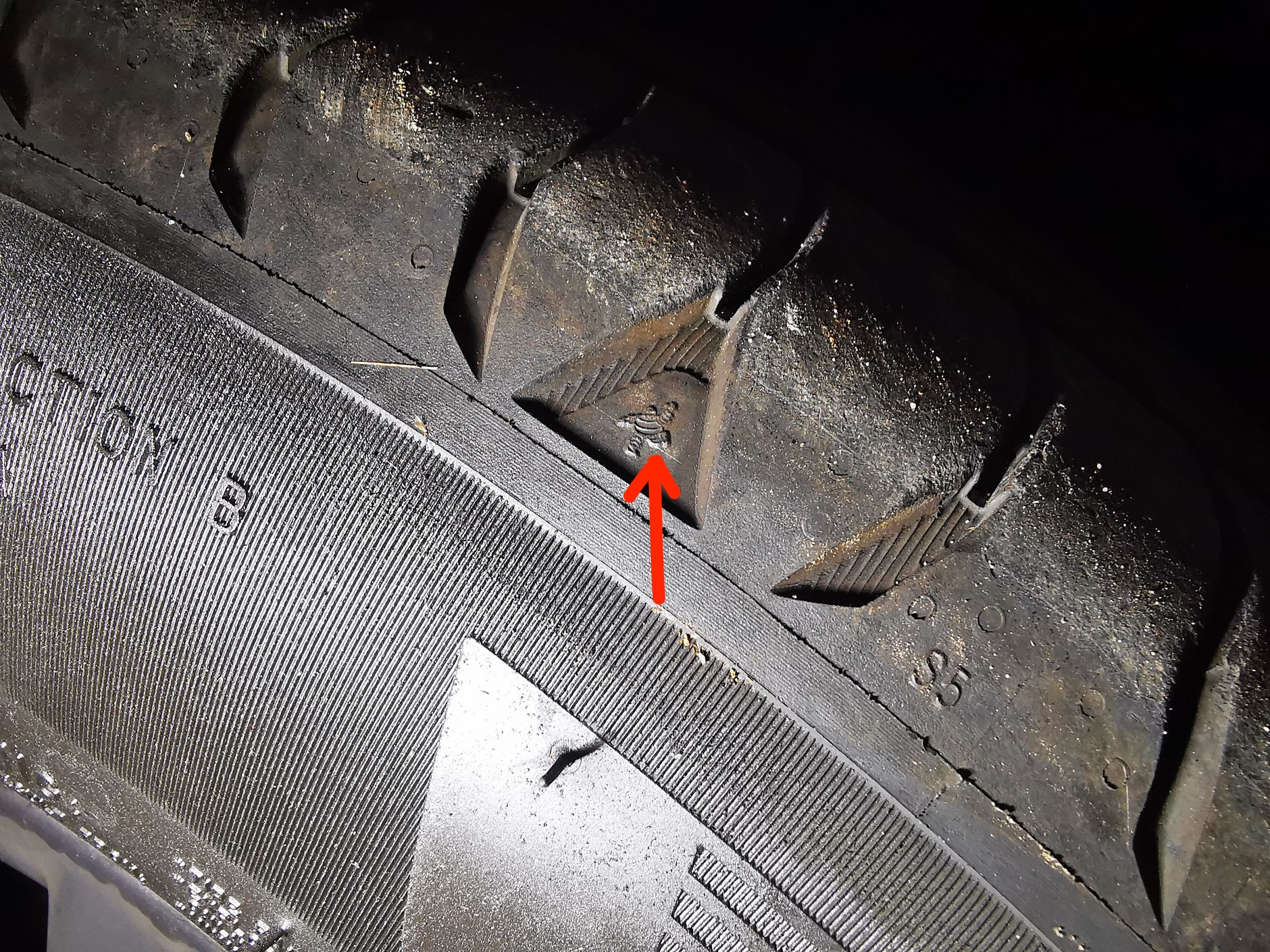 Opona Michelin – ludzik wskazuje, w ktorym punkcier obwodu oponu szukać wskaźnika zużycia na bieżniku