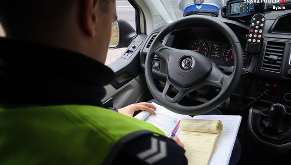 Policjant wypisujący mandat w radiowozie