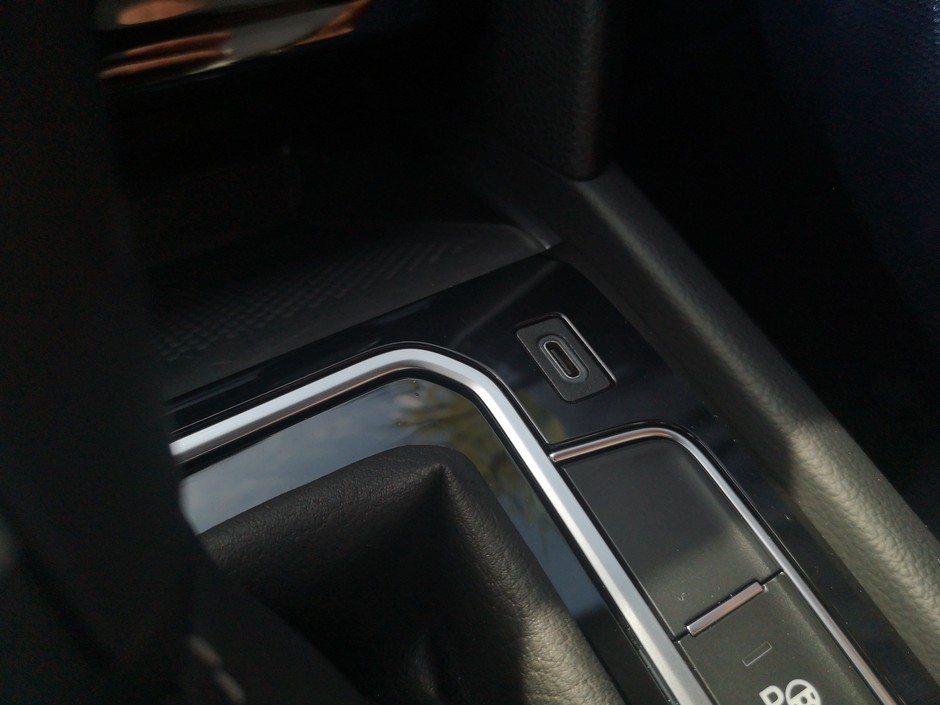 Gniazdo USB (teraz nowoczesny typ: USB-C) z wnęki powędrowało na tunel środkowy przy lewarku. Wygospodarowano w ten sposób miejsce na większy, współczesny telefon. Oczywiście płytka na telefon może mieć ładowanie indukcyjne