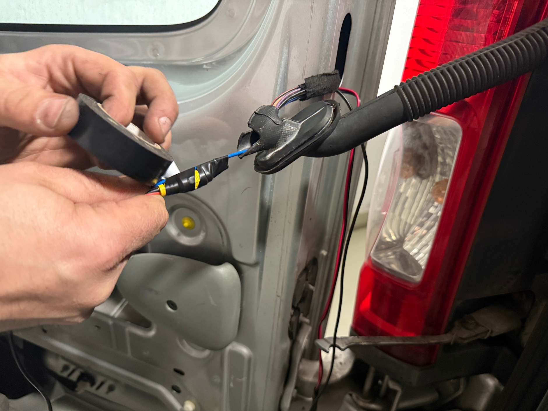 Największa przeszkoda: gumowy rękaw na wiązkę elektryczną już fabrycznie ciasno wypełniony przewodami. By przeprowadzić dodatkowe kable z wtyczką, użyliśmy drutu, do którego umocowaliśmy taśmą przewód z wtykiem