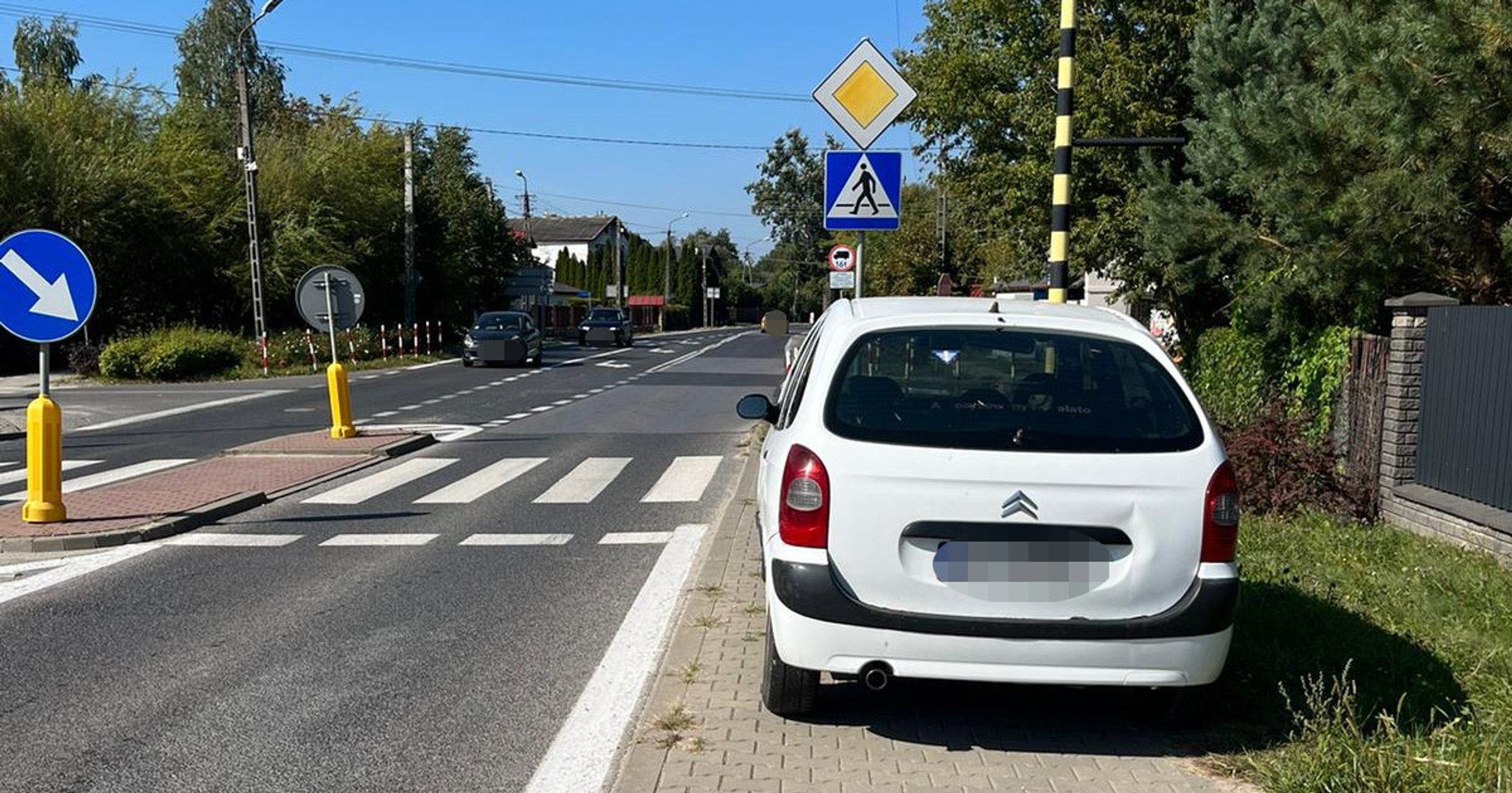 Biały Citroen zaparkowany na chodniku przed przejściem dla pieszych