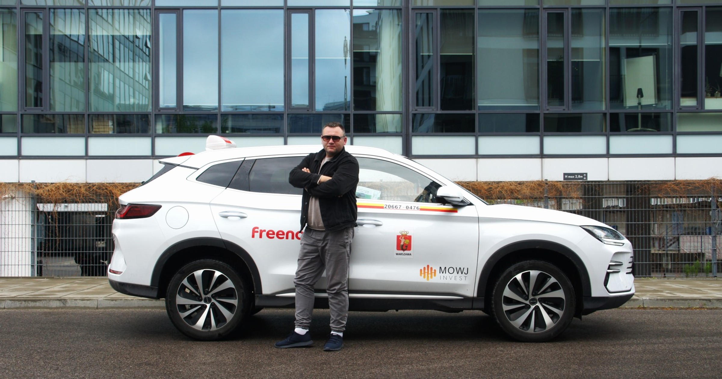 Taksówkarz Marcin Zawodzian na tle swojego chińskiego SUV-a marki BYD