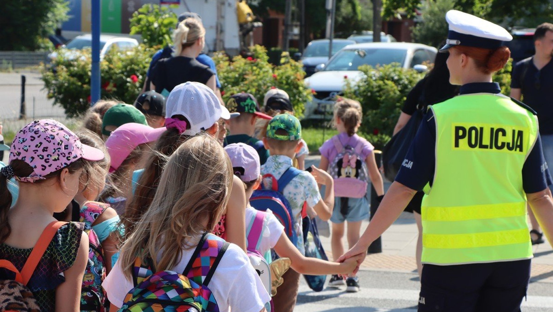Policjantka przeprowadzająca dzieci przez przejście dla pieszych