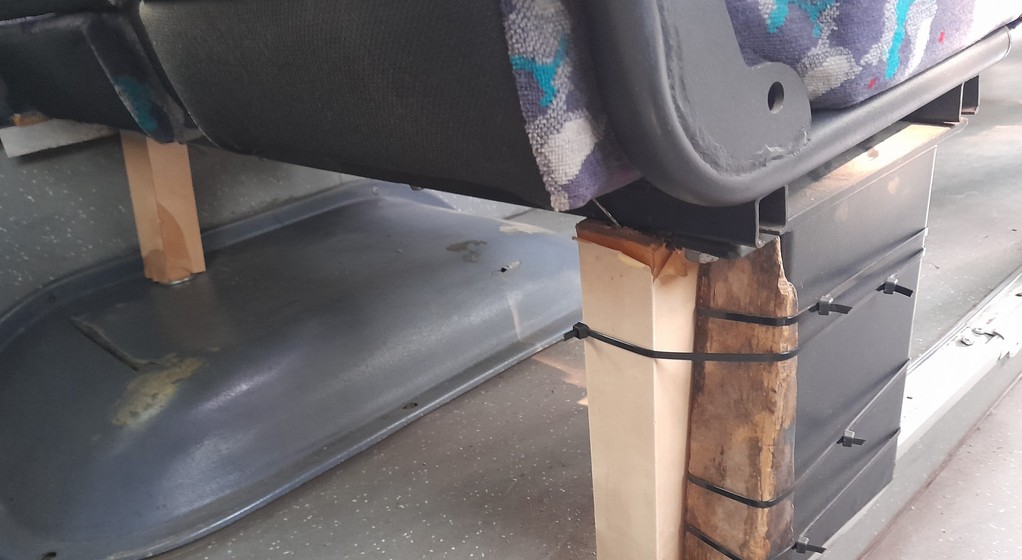 Autobus z fotelami na drewnianych klockach i z pękniętą felgą