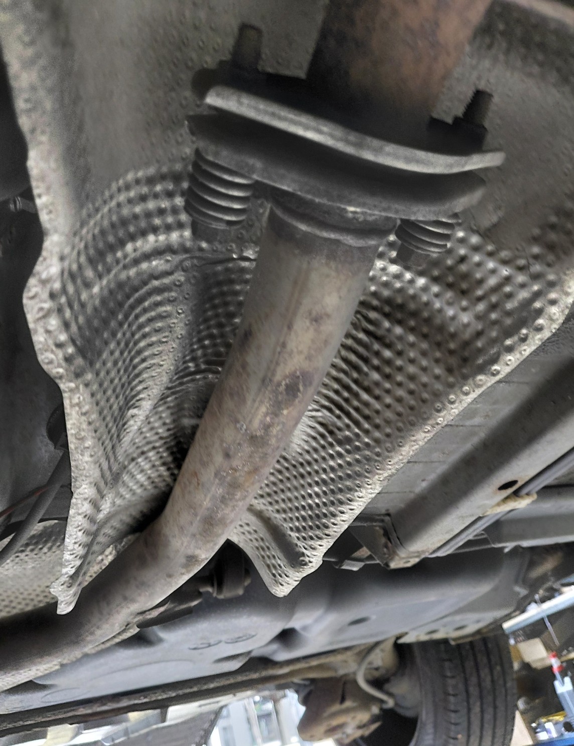 Przyczyna hałasów: urwane górne mocowanie osłony termicznej wydechu. Blacha opierała się o rurę, a przy zmianach przełożeń przenosiła wibracje na nadwozie. 