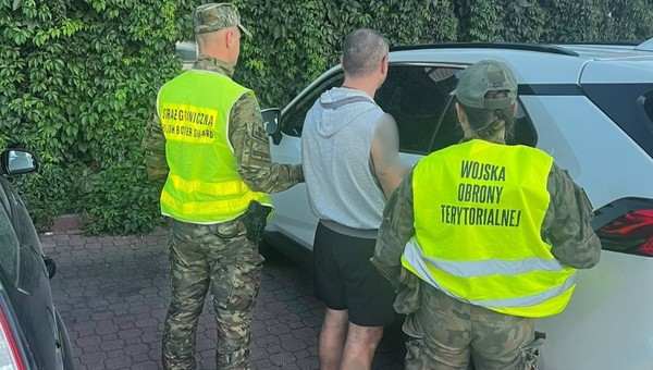 Funkcjonariusze Straży Granicznej i Wojsk Obrony Terytorialnej z zatrzymanym kierowcą na tle skradzionej Toyoty RAV4