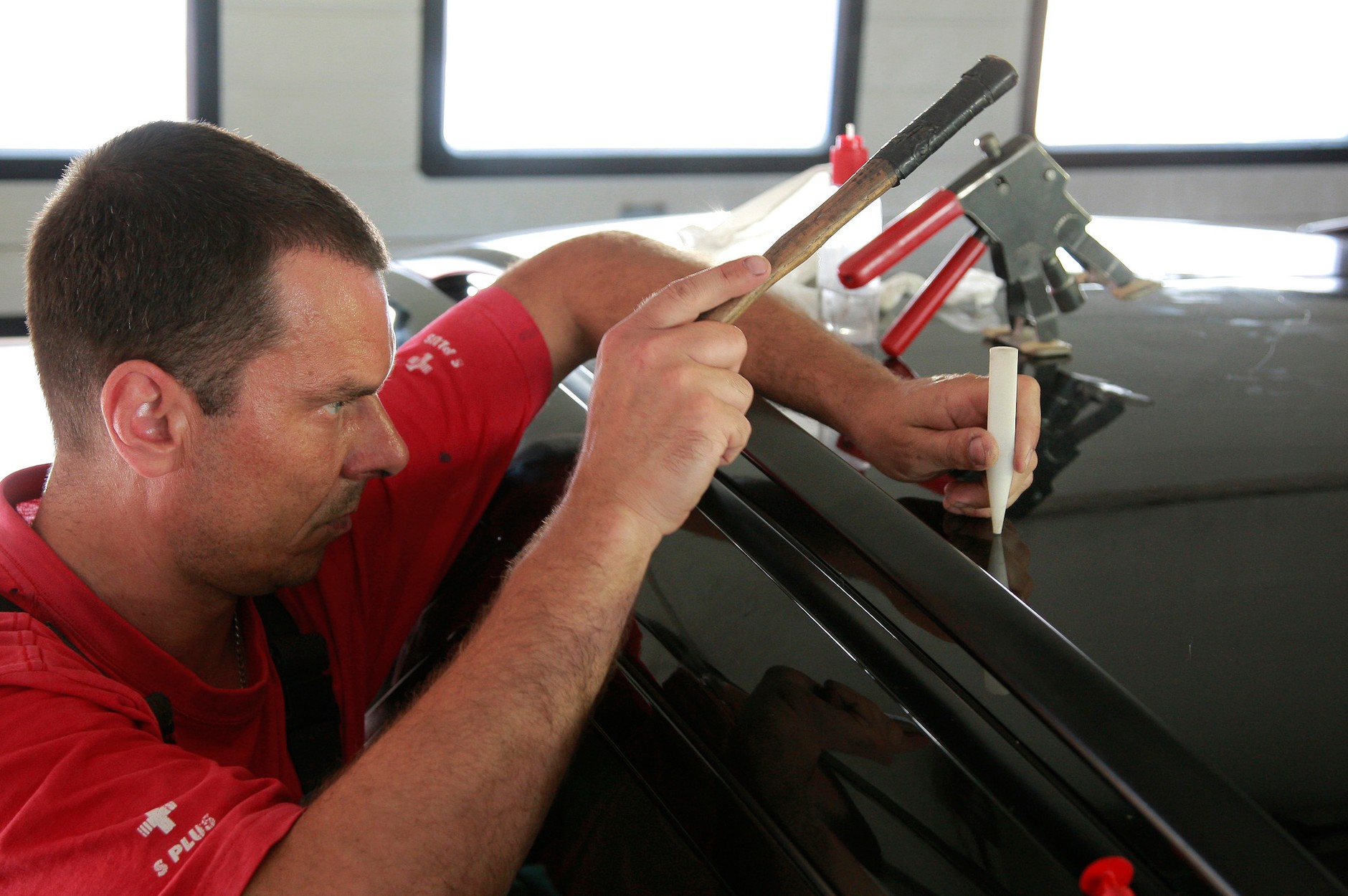 Prostowanie wgnieceń po gradobiciu: od zewnątrz zbyt mocno wypchniętą blachę uderza się młotkiem za pośrednictwem plastikowego pobijaka