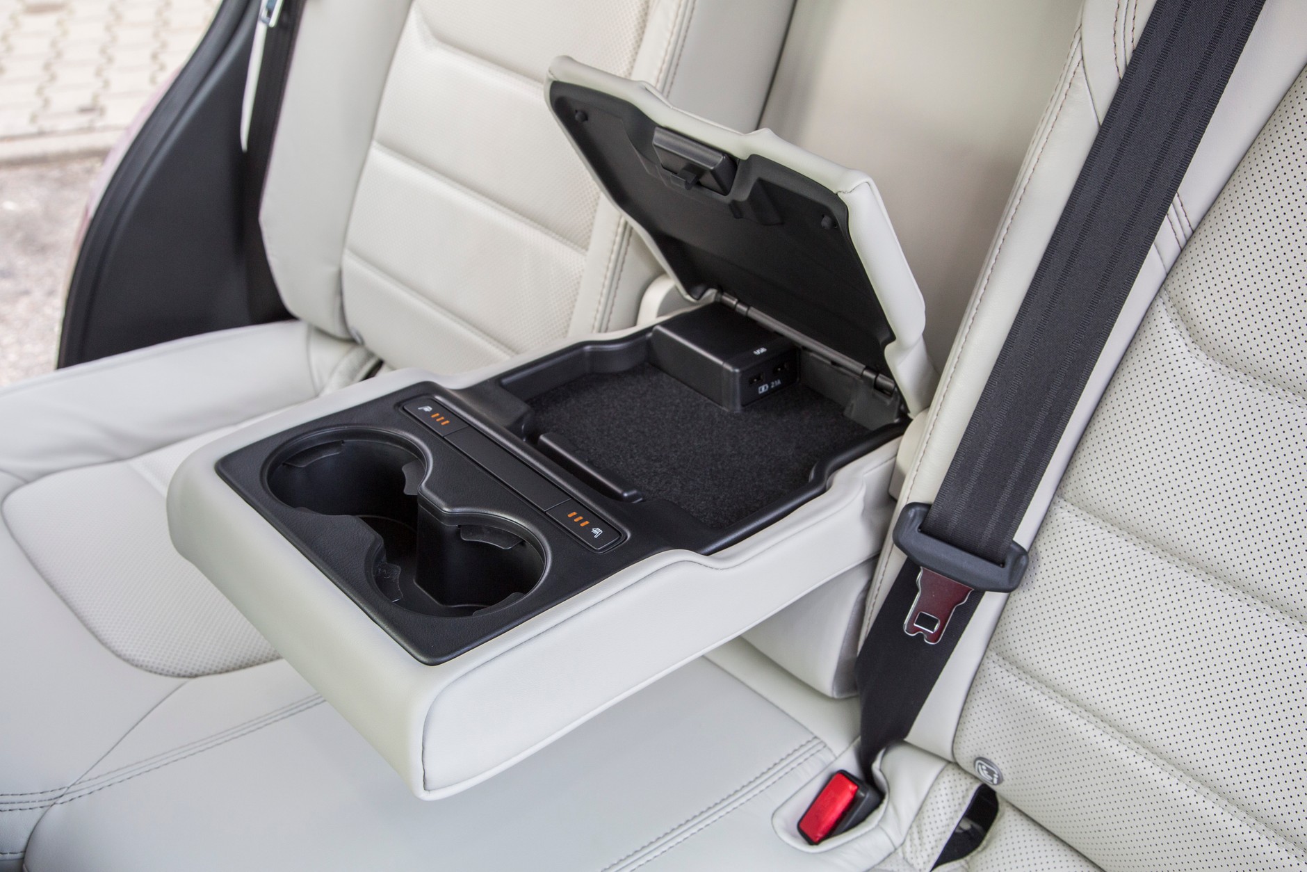 Podłokietnik tylny ma także funkcję schowka i uchwyty na napoje. Ukryto w nim sterowniki podgrzewania dla tylnych miejsc oraz dwa gniazda USB