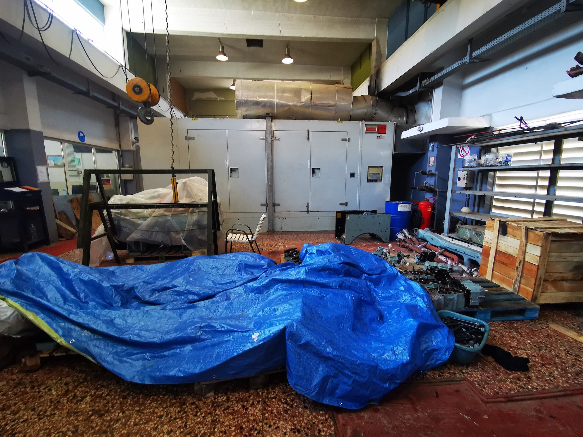 Wnętrze budynku elektrowni dieslowskiej na wyspie. Silnik wraz z generatorem zamknięty jest w metalowym kontenerze. Wokół panuje grecki porządek, na podłodze walają się części silnika, który akurat jest w remoncie.