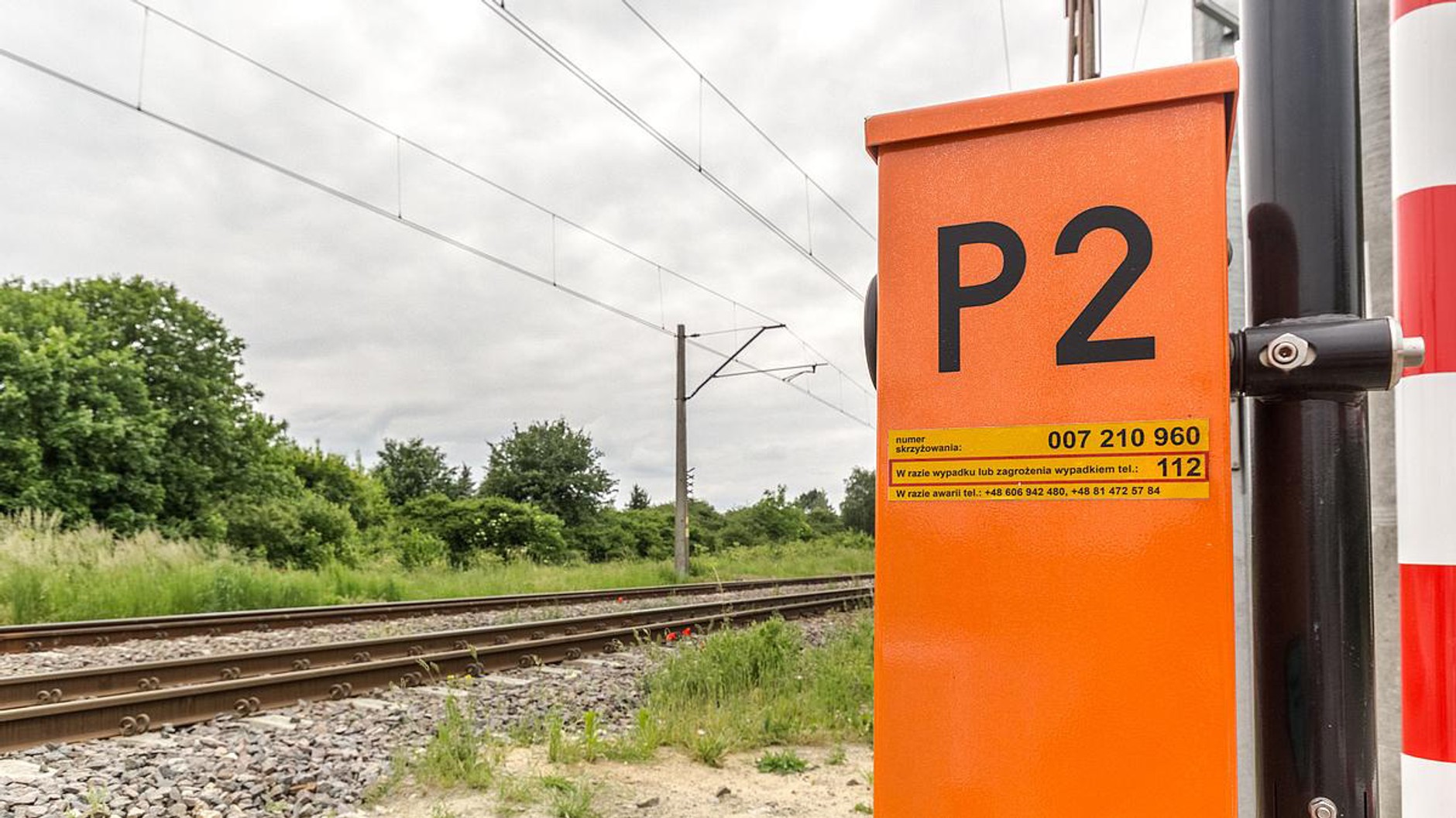 Żółta naklejka na przejeździe z rogatkami: znajdziesz ją na wsporniku rogatki