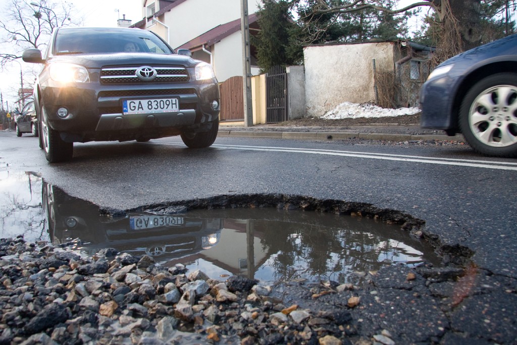 Dziurawa droga to zło. Jeśli tylko mamy możliwość, lepiej omijać odcinki ze zniszczoną nawierzchnią.