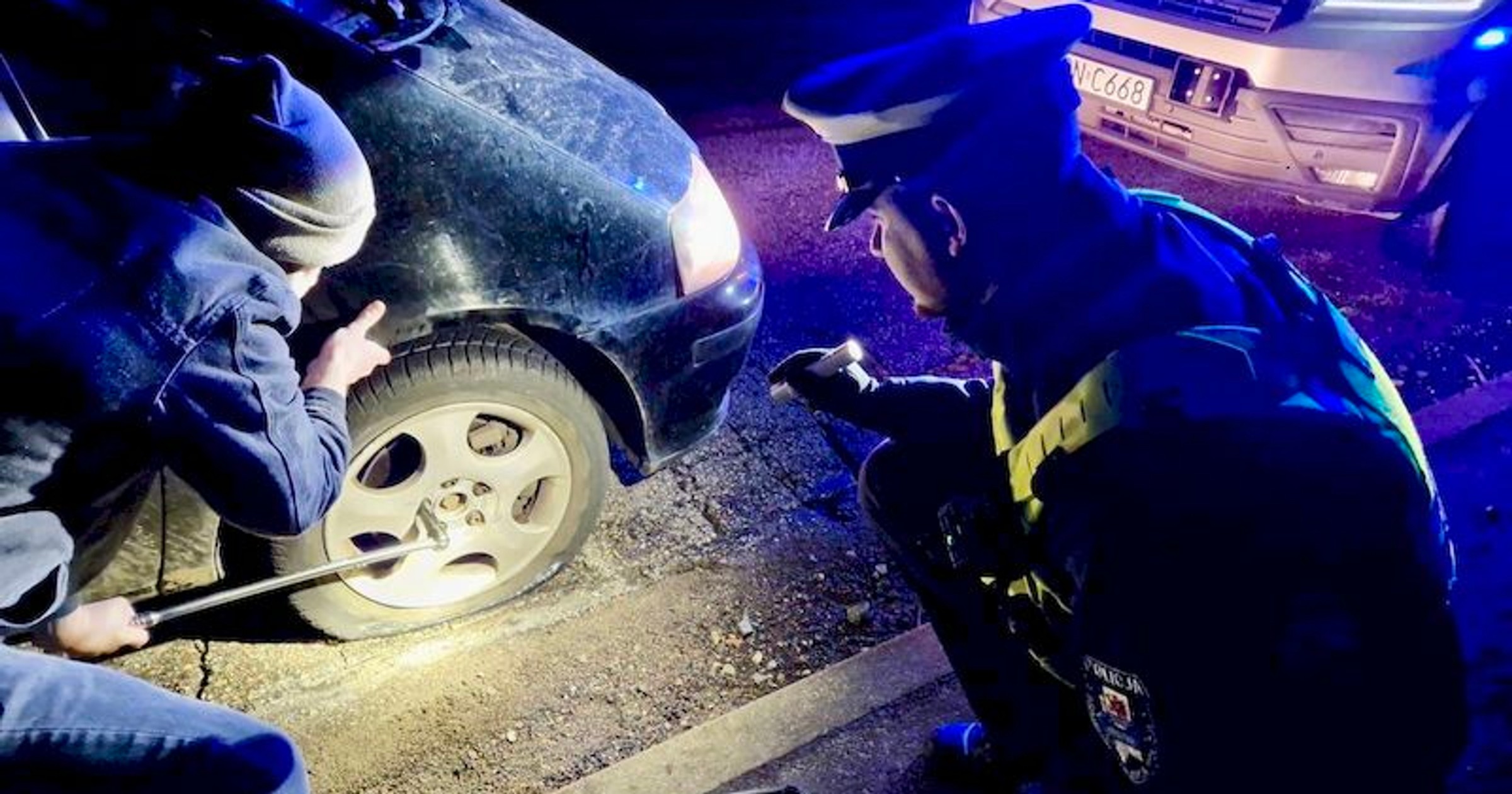 Policjanci pomagają kierowcom po uszkodzeniu kół na zniszczonej drodze