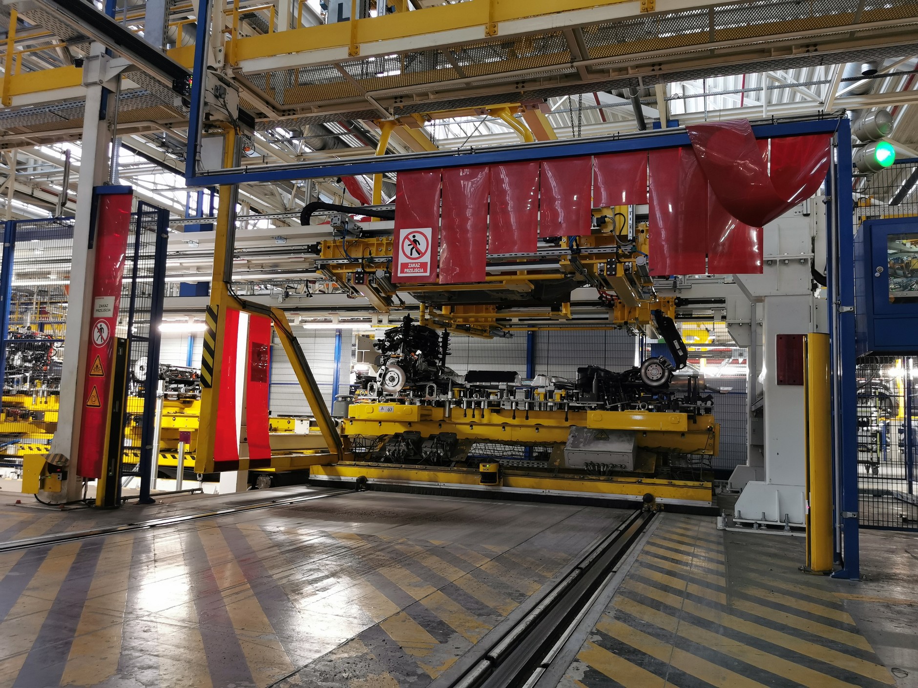 Na górze przesuwa się uzbrojone nadwozie, od dołu podjeżdża prawie kompletny zespół napędowy wraz z podwoziem umieszczony na platformie. Tu się spotkają i zostaną wstępnie skręcone, a na kolejnych stacjach kolejne roboty (ale też ludzie) będą dokręcać kolejne połączenia. Na tej samej platformie dostarczane są i spalinowe, i elektryczne zespoły napędowe wraz z baterią