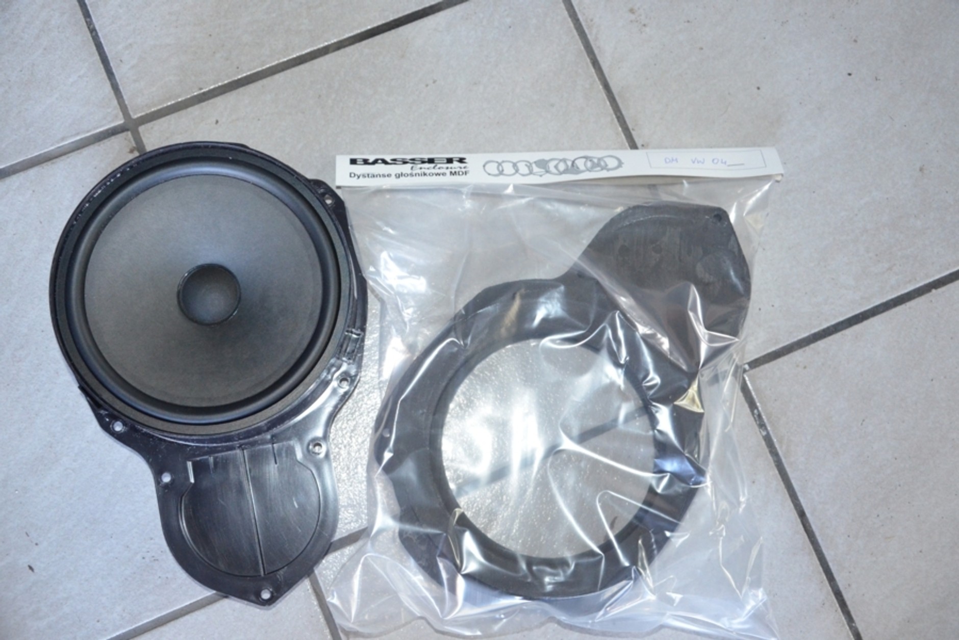 Woofer po demontażu z przednich drzwi. Z lewej strony głośnik fabryczny zintegrowany z plastikowym koszem mocującym.